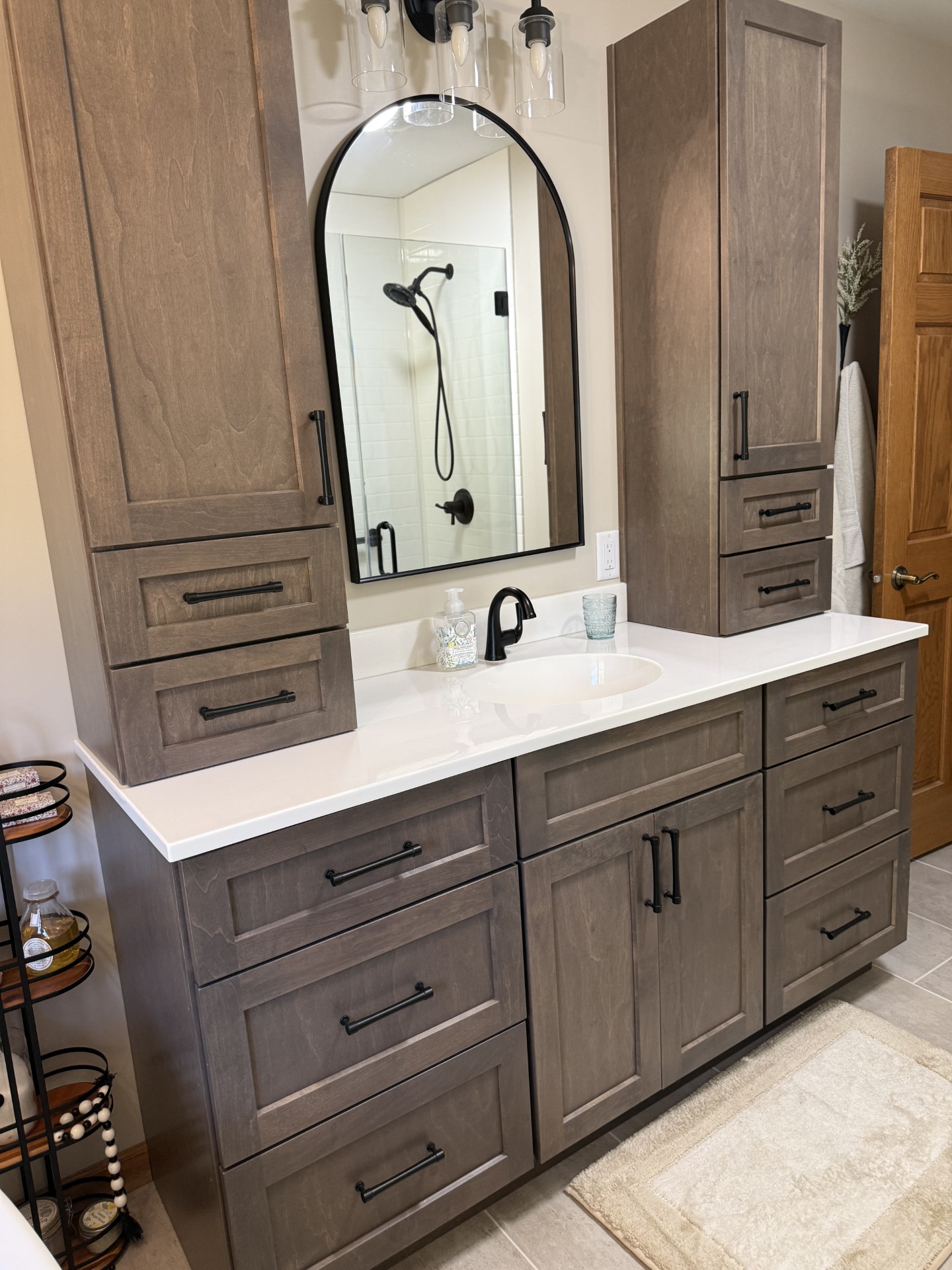 Gray vanity with quartz countertop and arched mirror