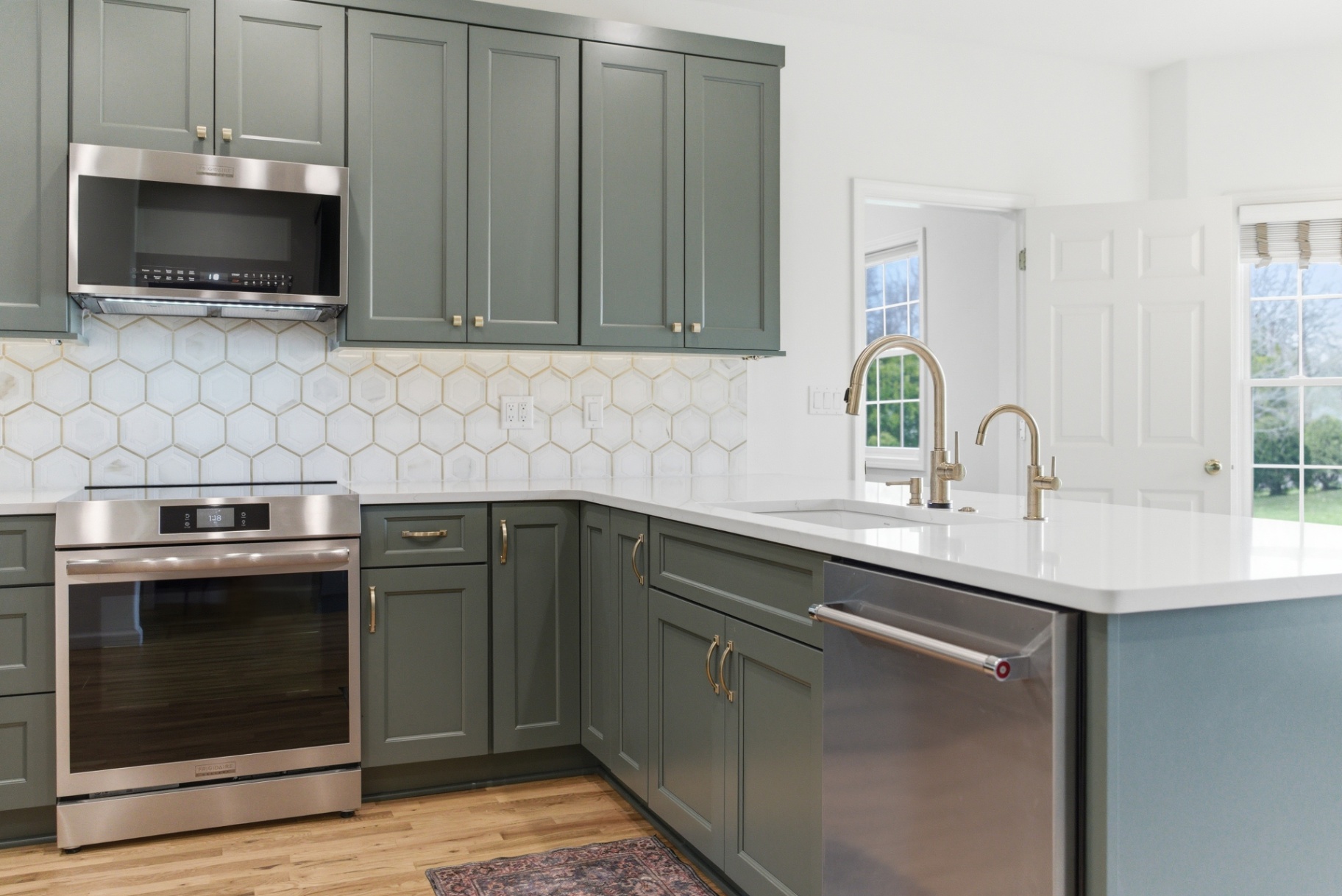 Sage kitchen cabinetry with brass hardware and professional range in Waterloo Iowa