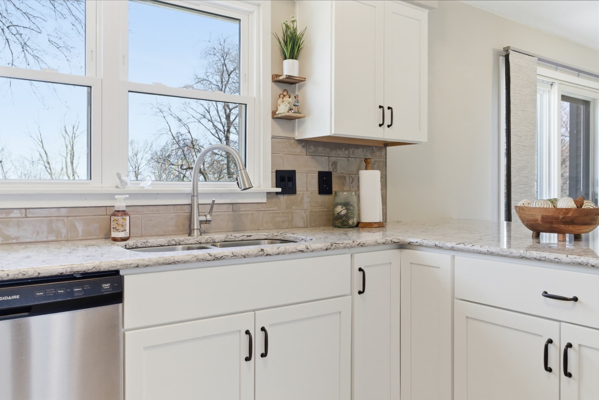 Finished kitchen sink beneath the window with white cabinets and countertops