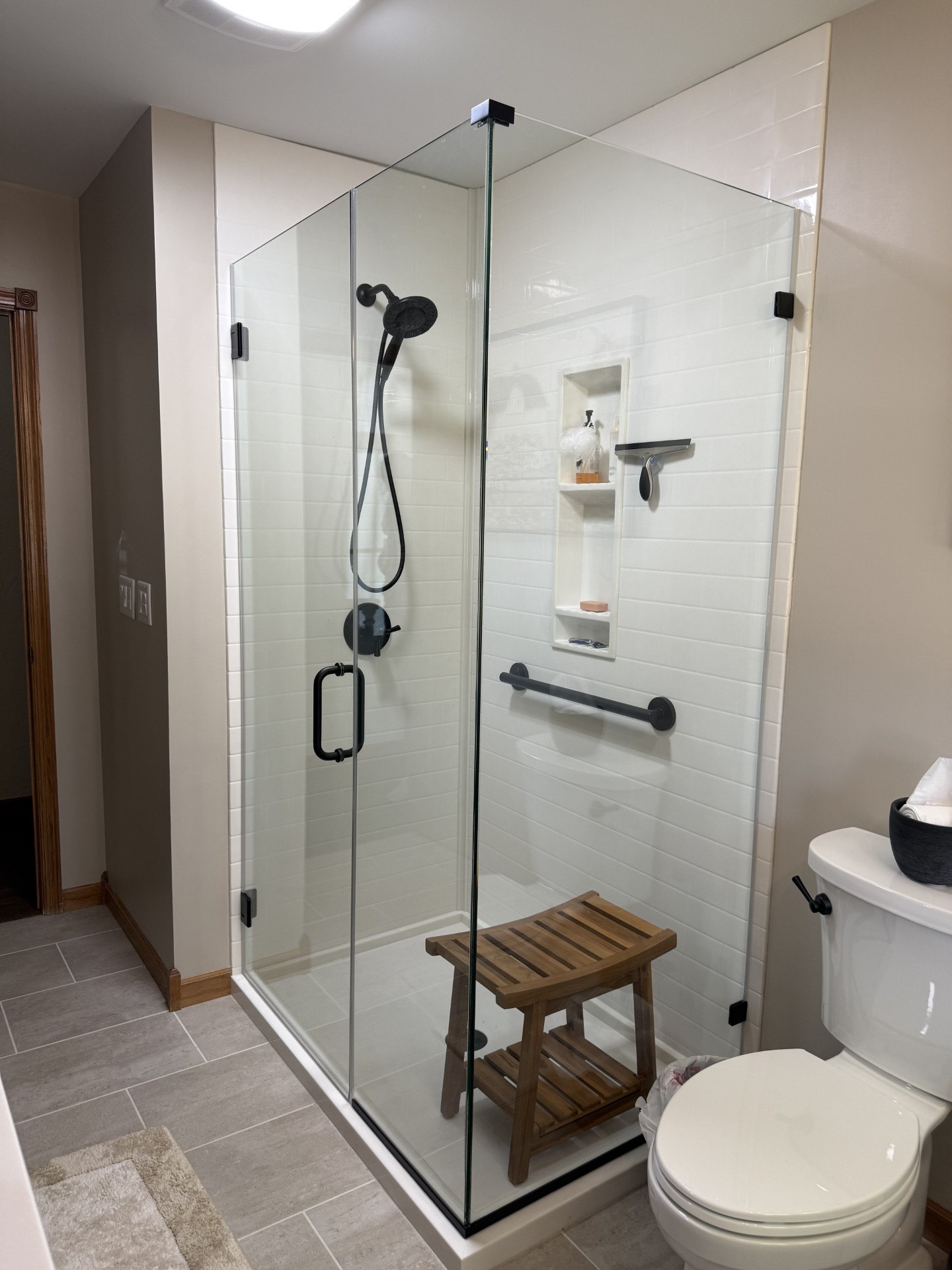 White subway tile walk-in shower with bench and black fixtures