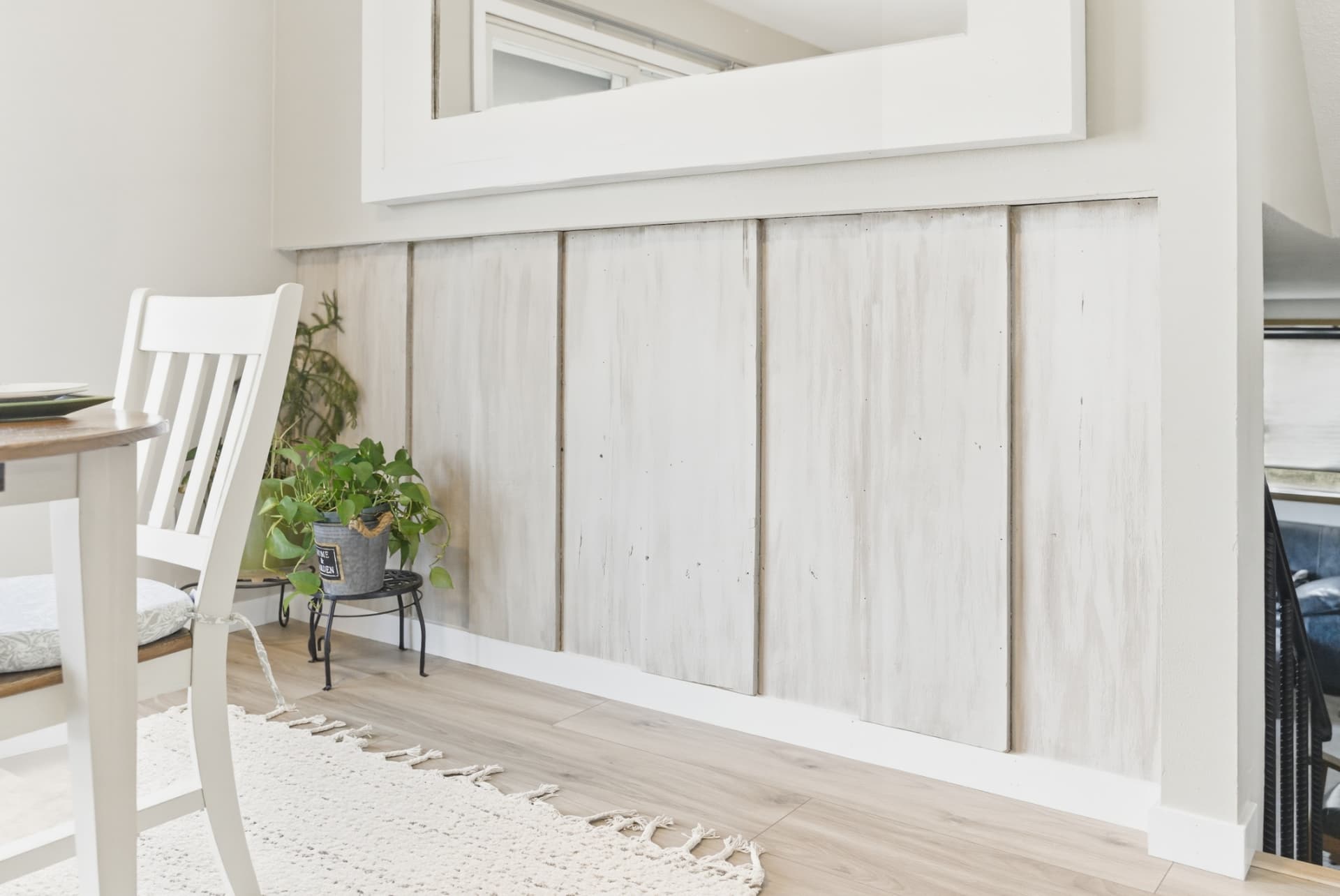 Finished dining area with light plank flooring and white paneled wall
