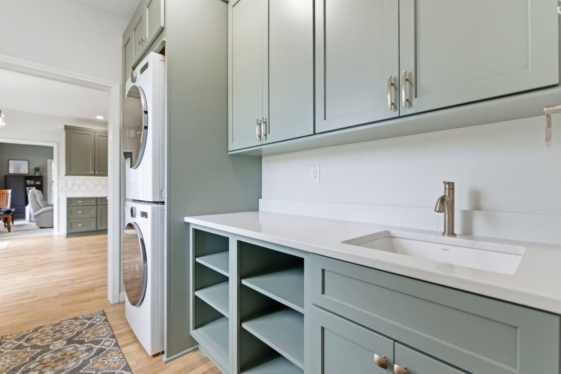Laundry room utility sink with brushed-nickel faucet, quartz counter, and sage cabinetry