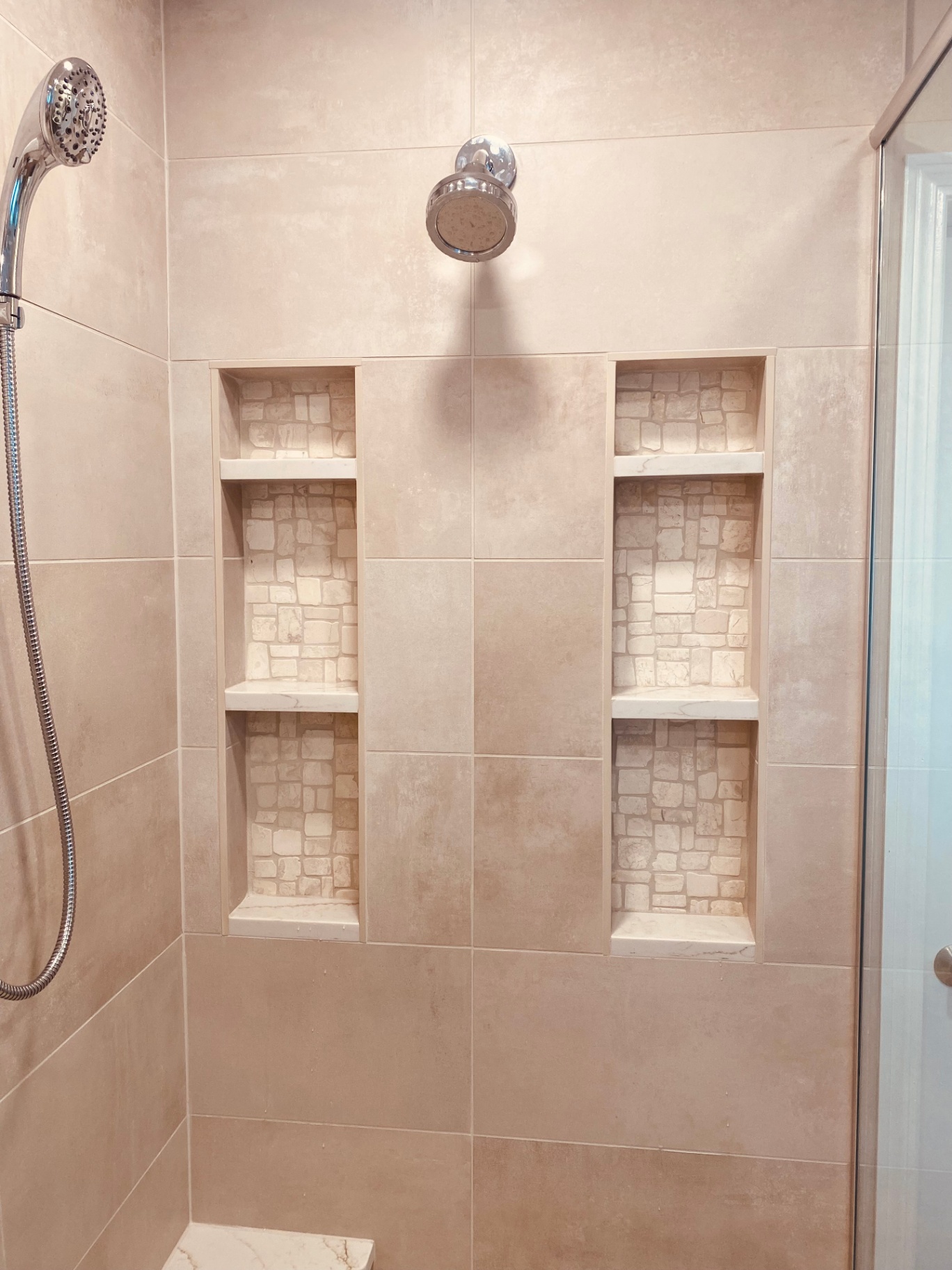 Recessed shower niches with stone accent tile in a remodeled shower
