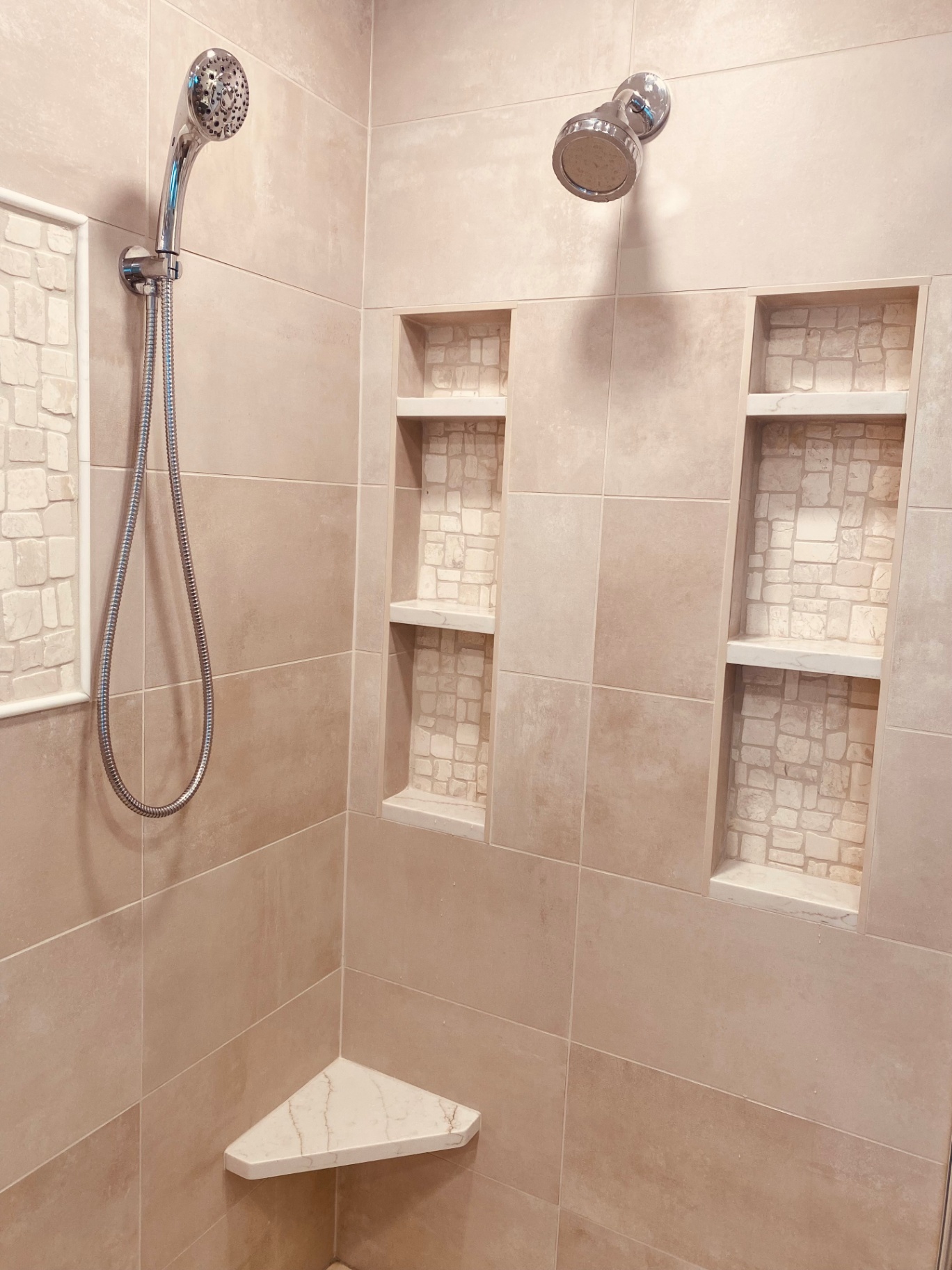 Close-up of shower niches with stone mosaic backs and marble shelves