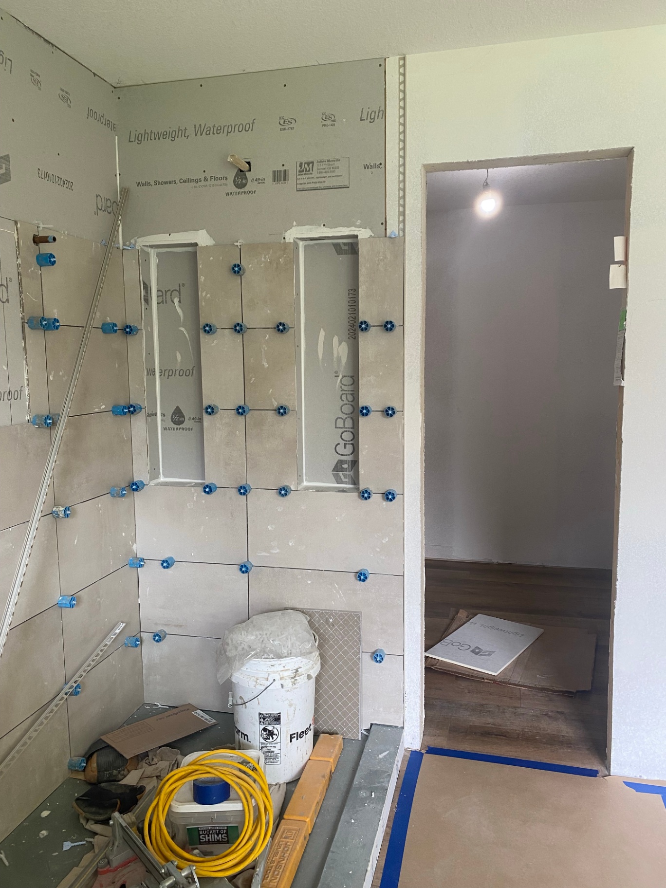 Bathroom under construction in Cedar Falls with shower tile being installed and recessed niches taking shape