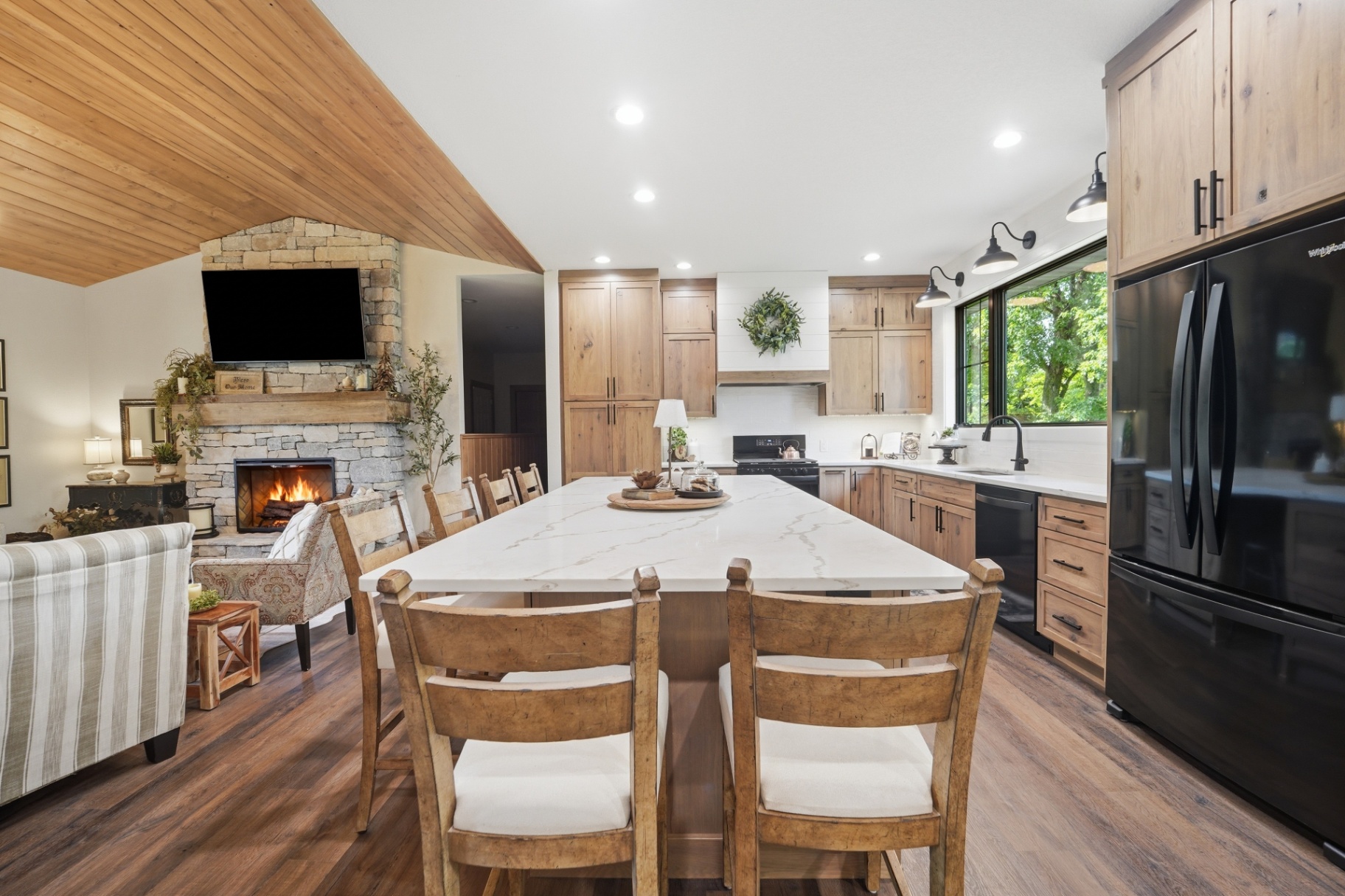 Finished kitchen island opening to the vaulted living room and stone fireplace