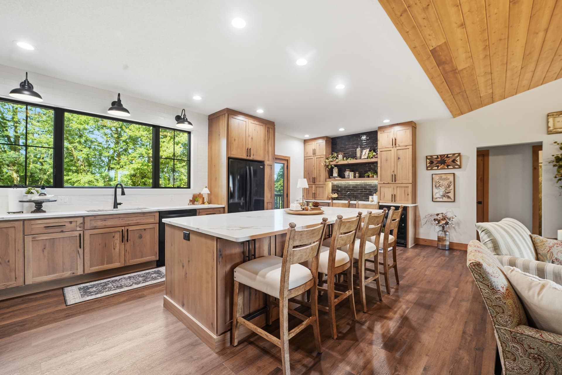 Kitchen sink wall and island with the wet bar and black backsplash beyond