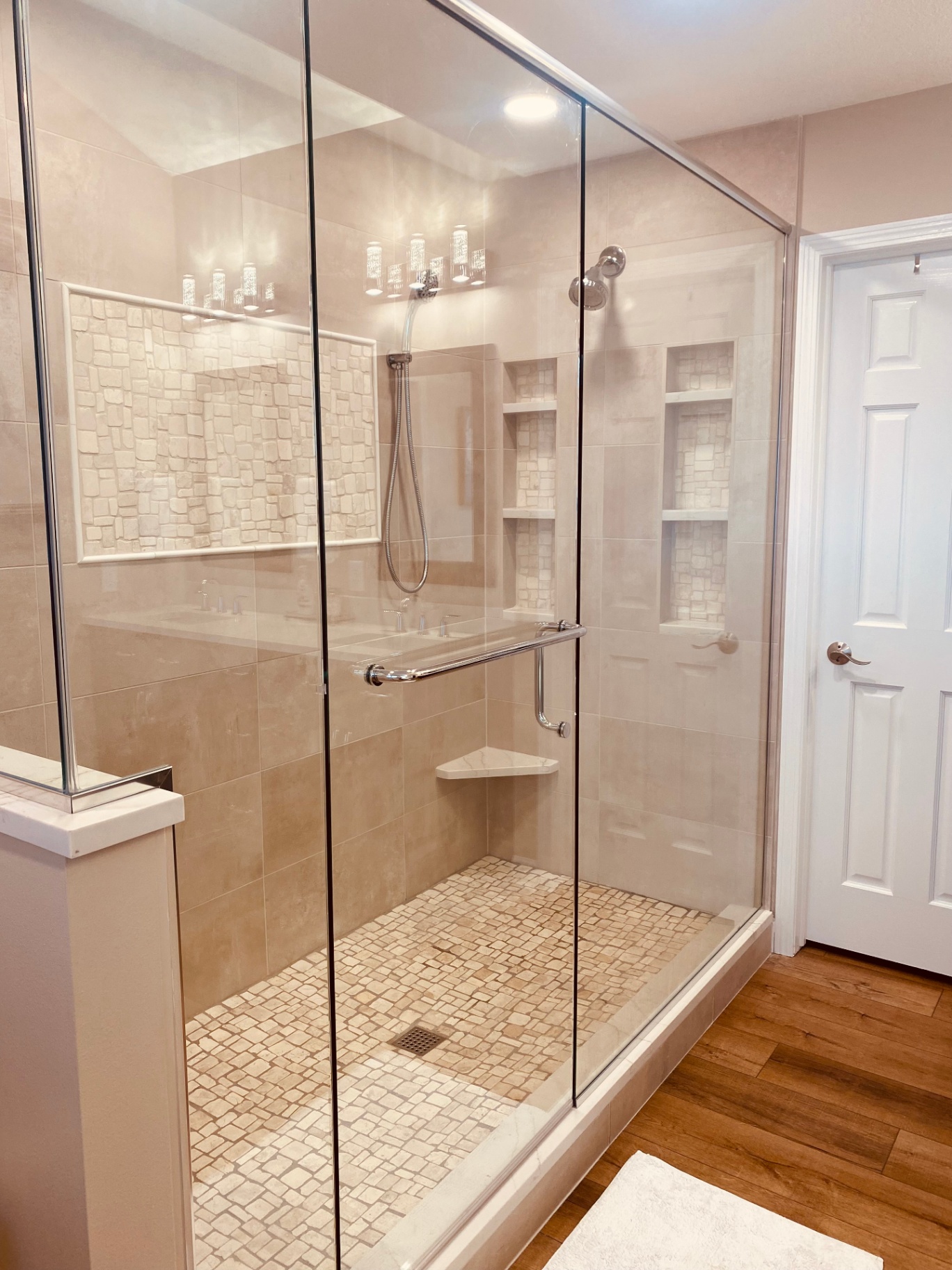 Angled view of the finished glass shower with mosaic accent wall and stacked niches