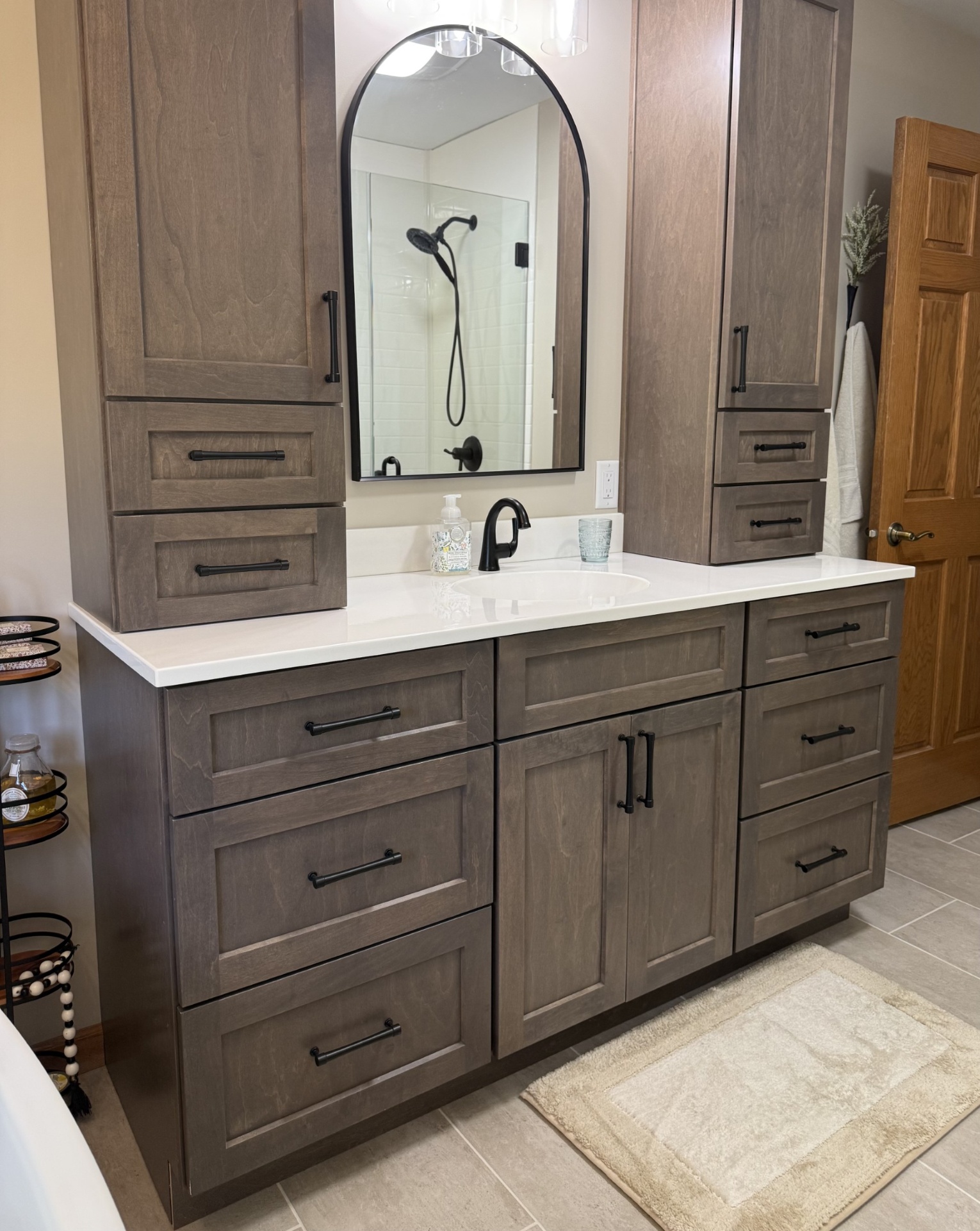 Detailed view of stained maple vanity cabinetry, integrated Onyx top, and matte black hardware