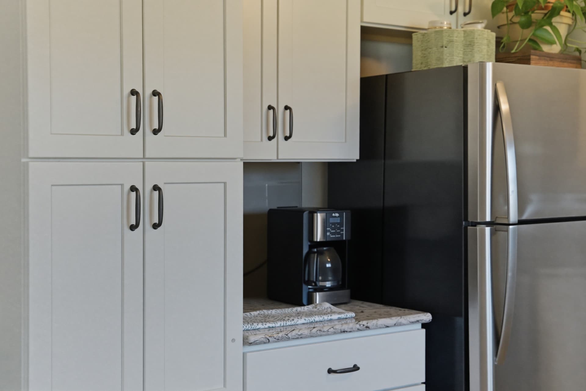 Finished white pantry cabinets with dark pulls beside the refrigerator in the Cedar Falls kitchen