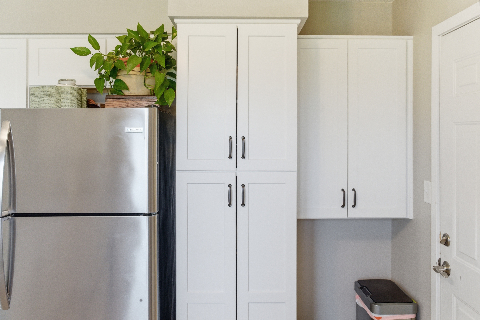 Tall white pantry cabinet next to refrigerator in Cedar Falls kitchen